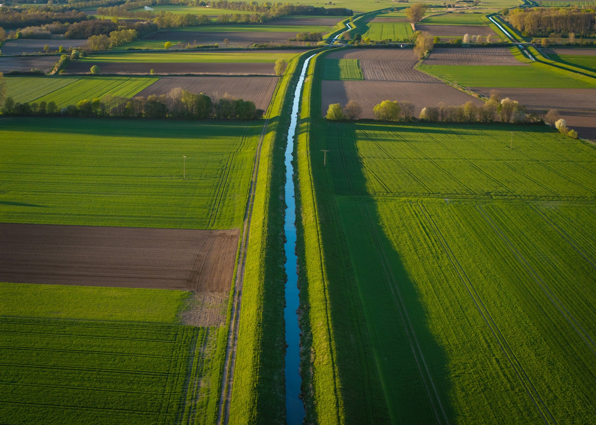 Straight irrigation canal running between farm fields, seen from above