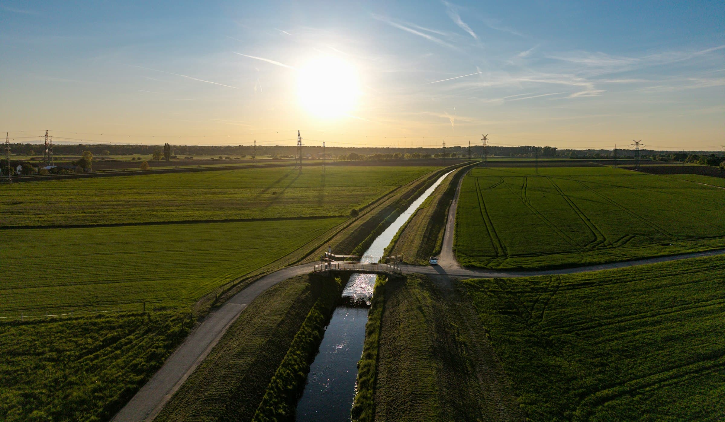 Irrigation canal crossing green fields at sunset